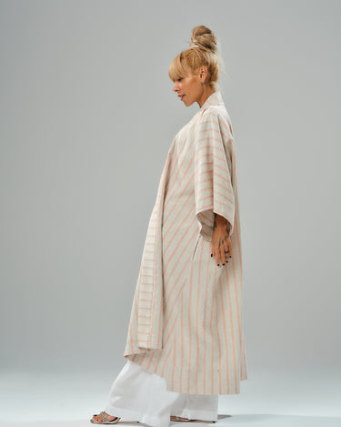 Side view of a woman wearing a striped linen-cotton kimono, styled over white wide-leg pants.