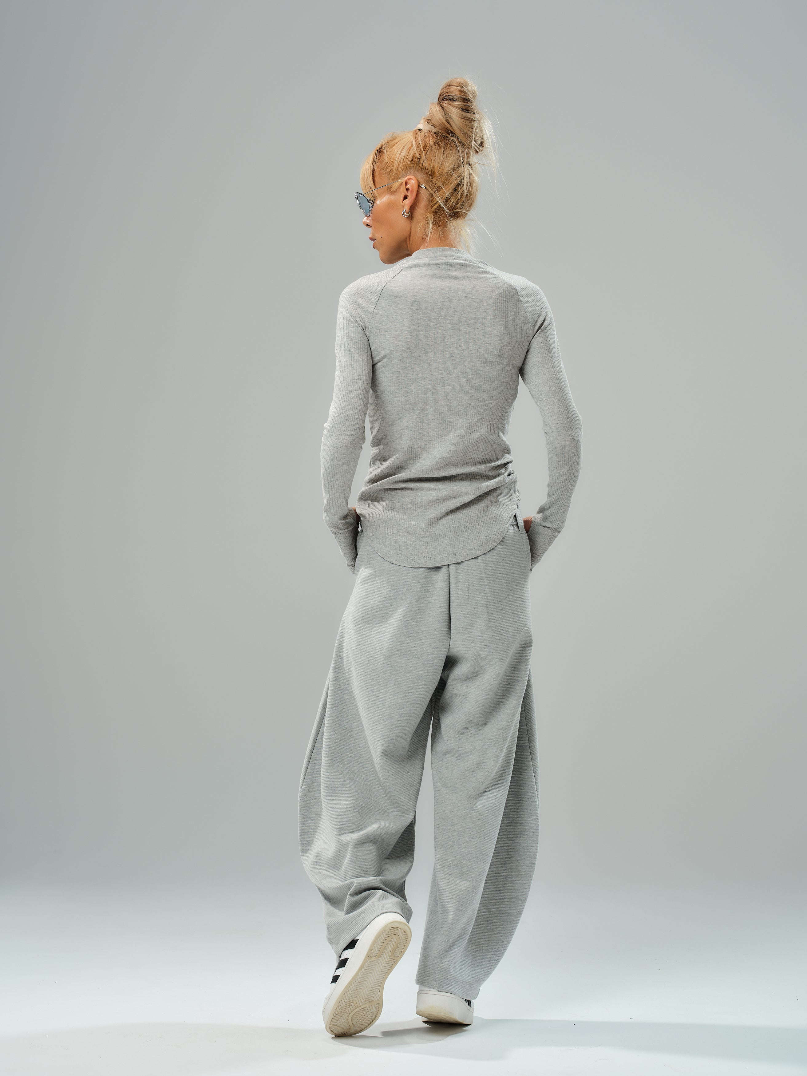 Model wearing a fitted long-sleeve gray top and oversized gray wide-leg trousers from the three-piece set.