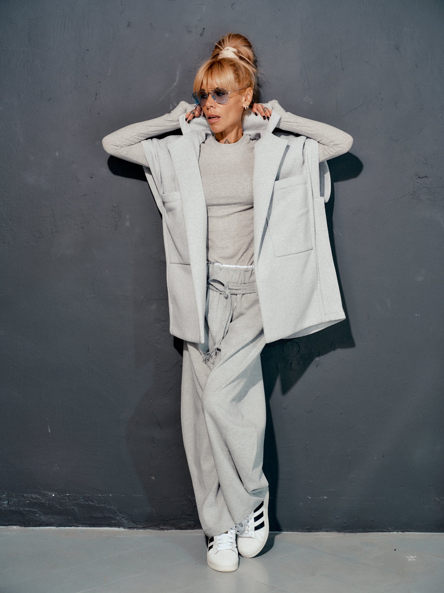 Model wearing oversized grey three-piece set with sleeveless vest, ribbed top, and wide-leg trousers.