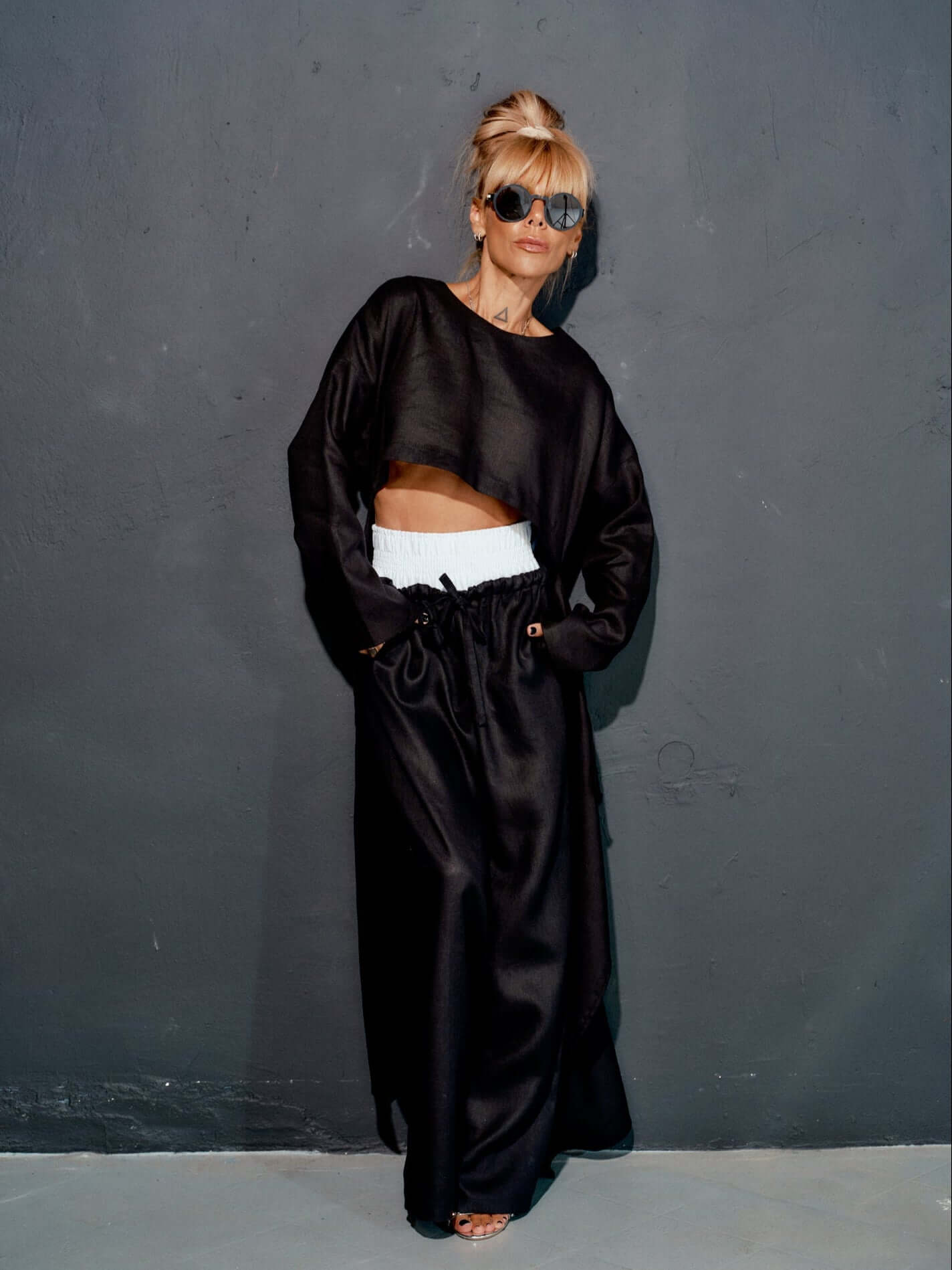 Model wearing a stylish black co-ord set with a crop top and wide-leg pants against a dark background.