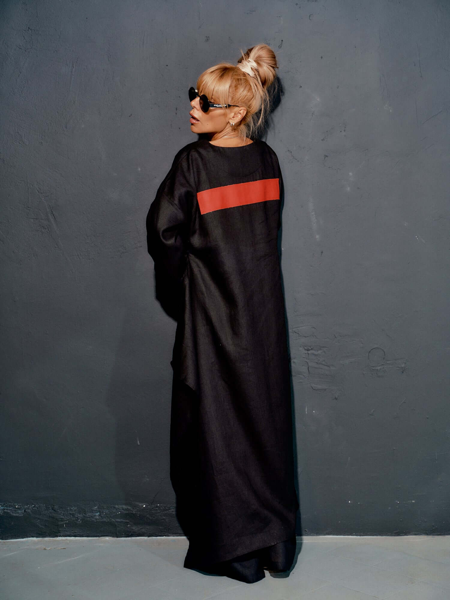 Model wearing a black co-ord set tunic with red stripe, showcasing a minimalist and modern fashion style.