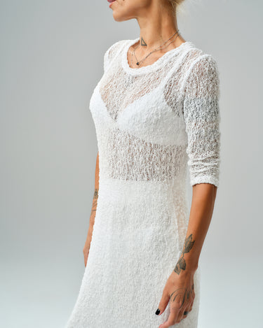 Profile view of a woman wearing a sheer white tunic from a maxi co-ord set, showcasing textured fabric.