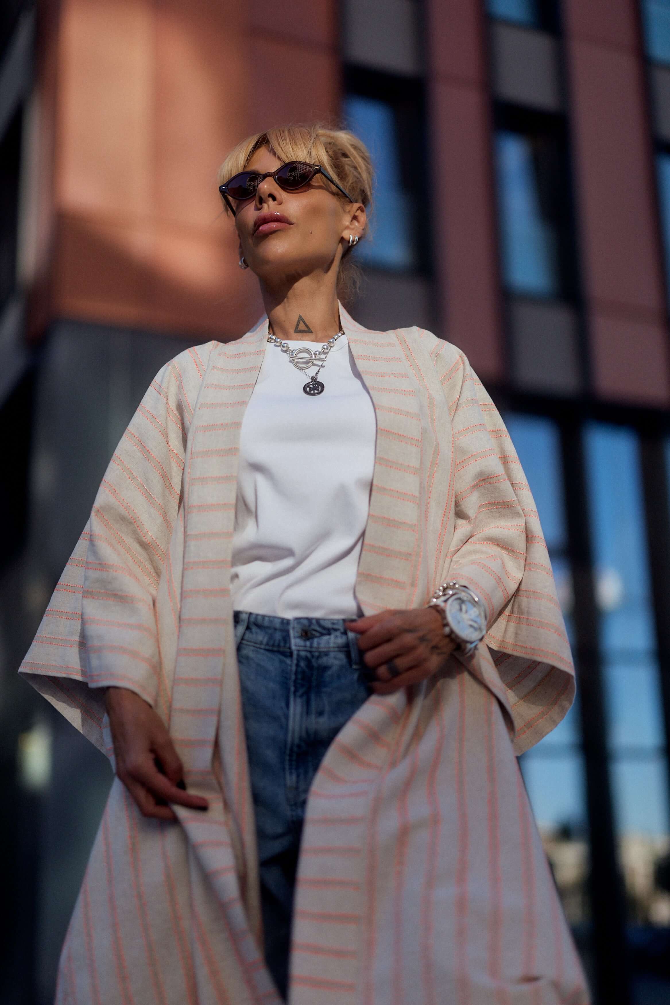 Woman wearing a striped linen-cotton kimono over a white top and denim, showcasing a relaxed and elegant style.