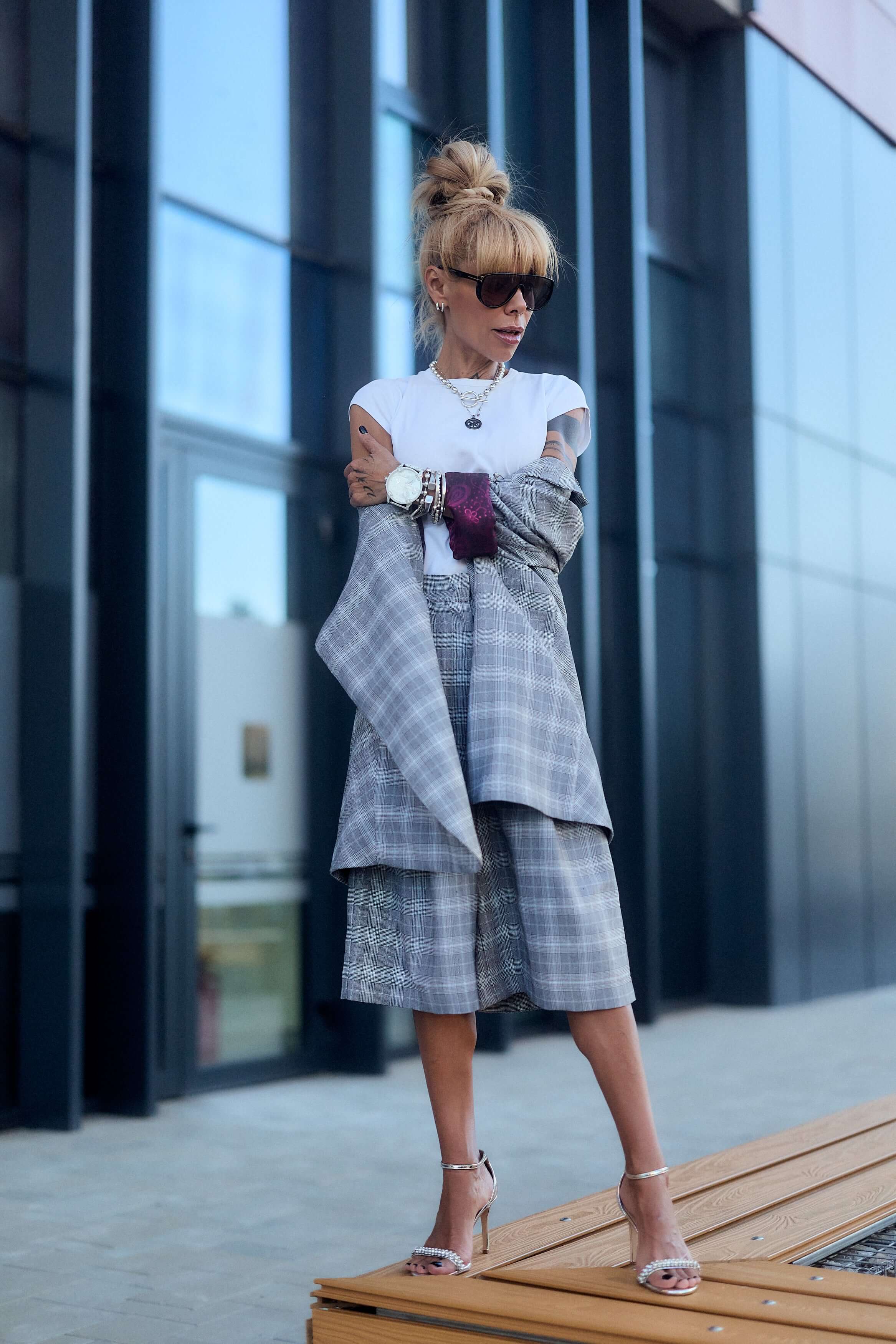 Model wearing a light grey checked blazer and culotte co-ord set with oversized fit and burgundy detail.