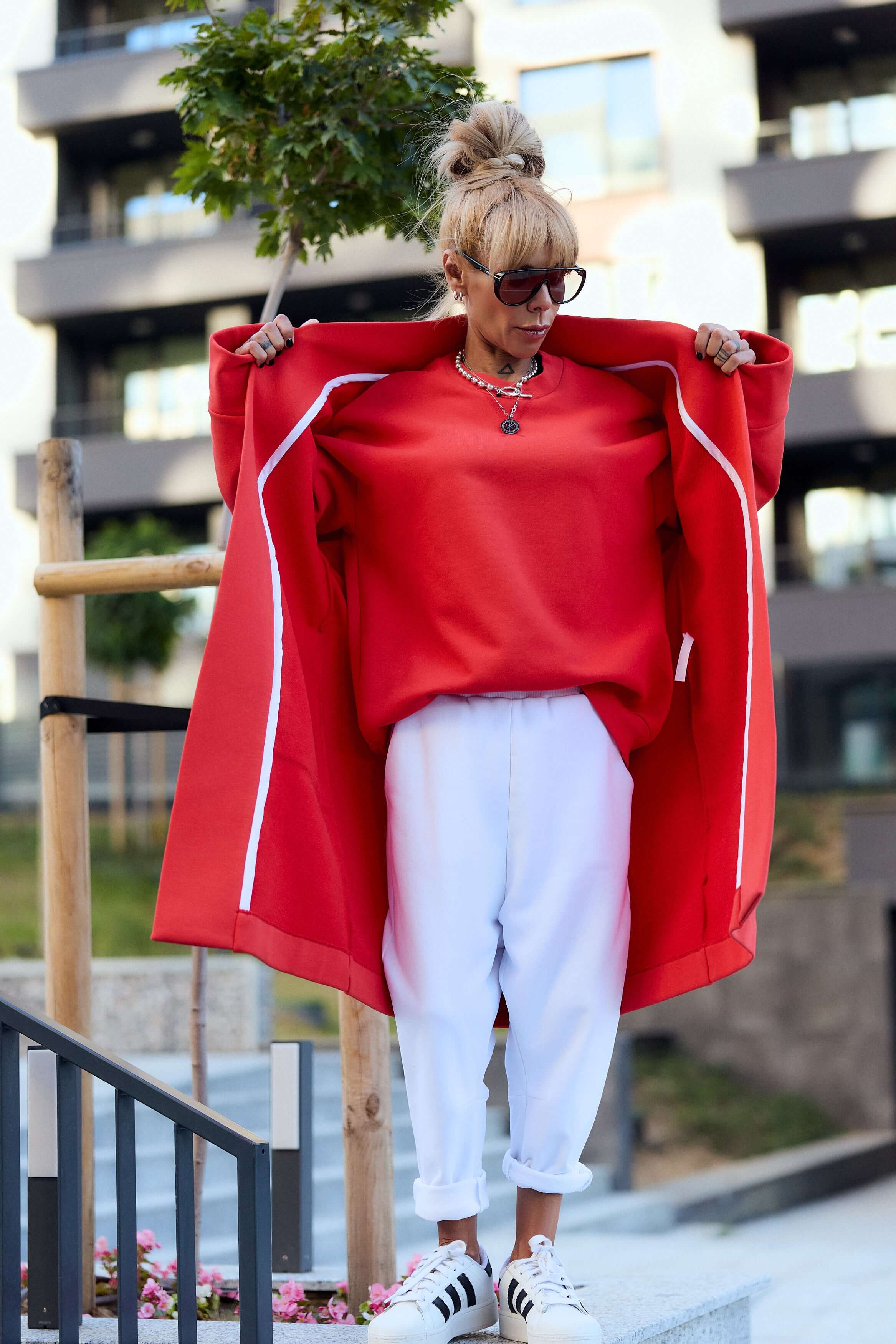 Stylish woman in a red oversized coat and white pants, showcasing a relaxed, bold outfit perfect for casual styling.