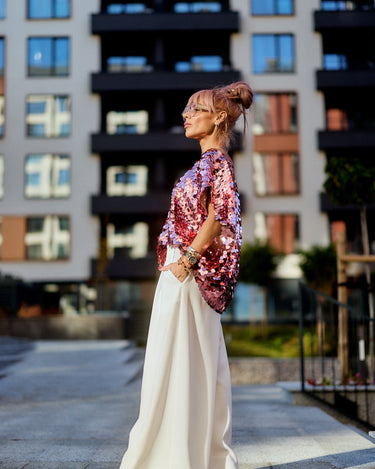 Model wearing a Pink Sequin Oversized Top, showcasing its vibrant sequins against a modern urban backdrop.