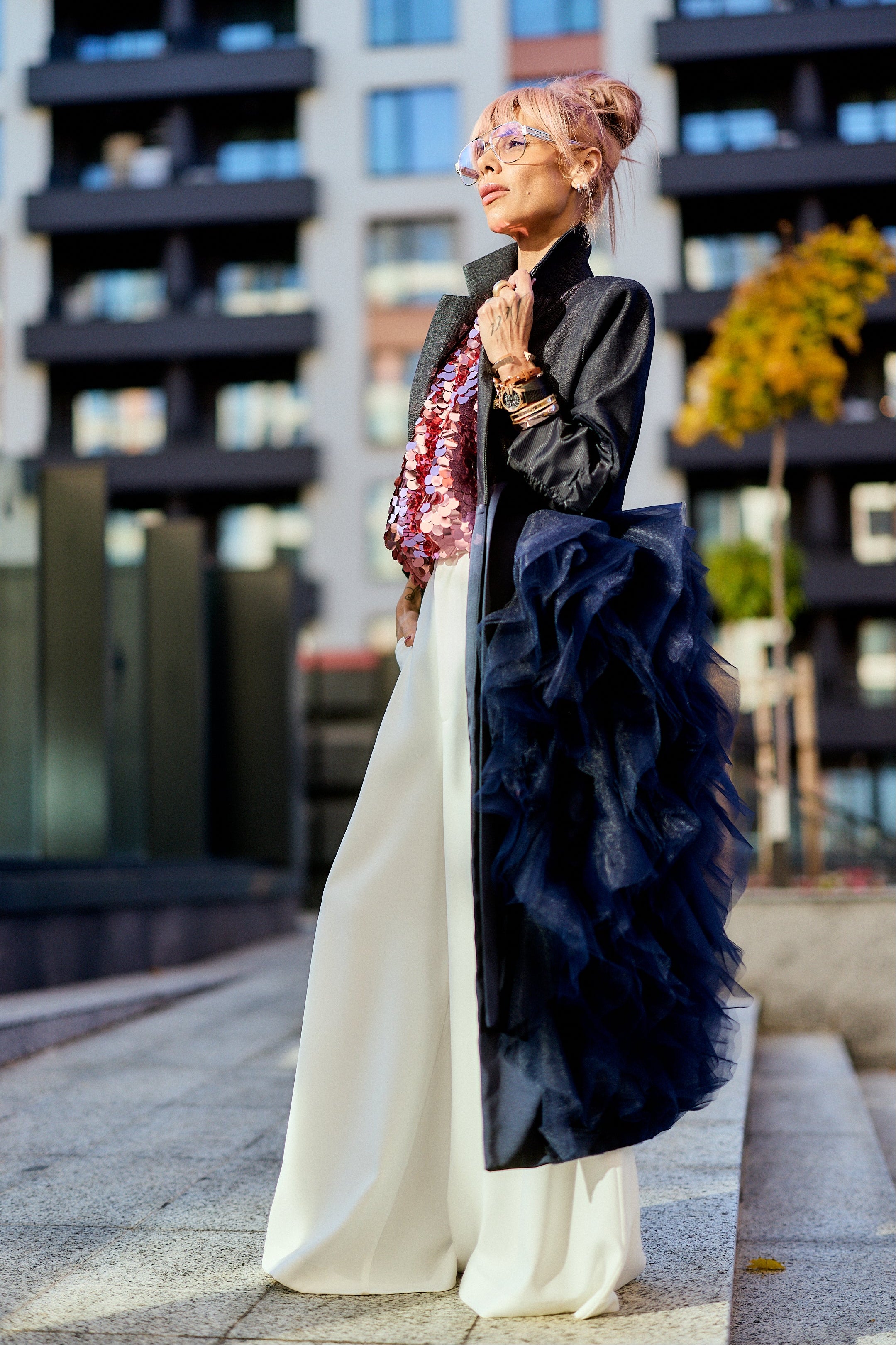 Model showcasing the Denim Tulle Detail Blazer with tulle ruffle, styled with wide-leg pants in an urban setting.