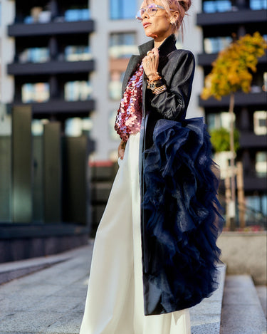 Model showcasing the Denim Tulle Detail Blazer with tulle ruffle, styled with wide-leg pants in an urban setting.
