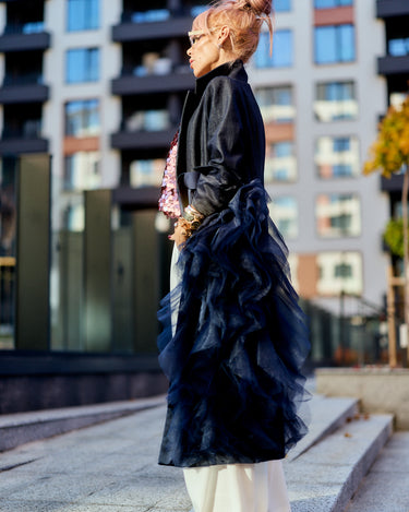 Side view of a model wearing a Denim Tulle Detail Blazer with tulle ruffle cascading down, styled for urban fashion.
