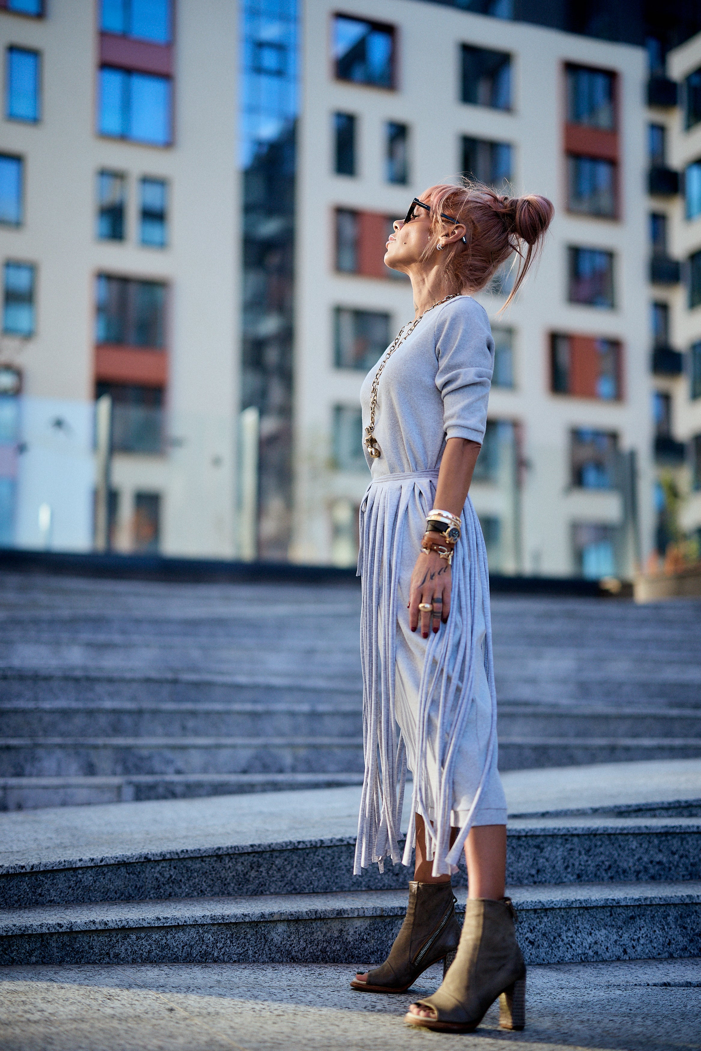Model wearing a Grey Fringe Midi Dress, showcasing its dramatic fringe and high-waisted silhouette in an urban setting.