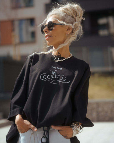 Black Oversized “I’m Fine” Graphic T-Shirt worn by a model in a sunny urban setting.