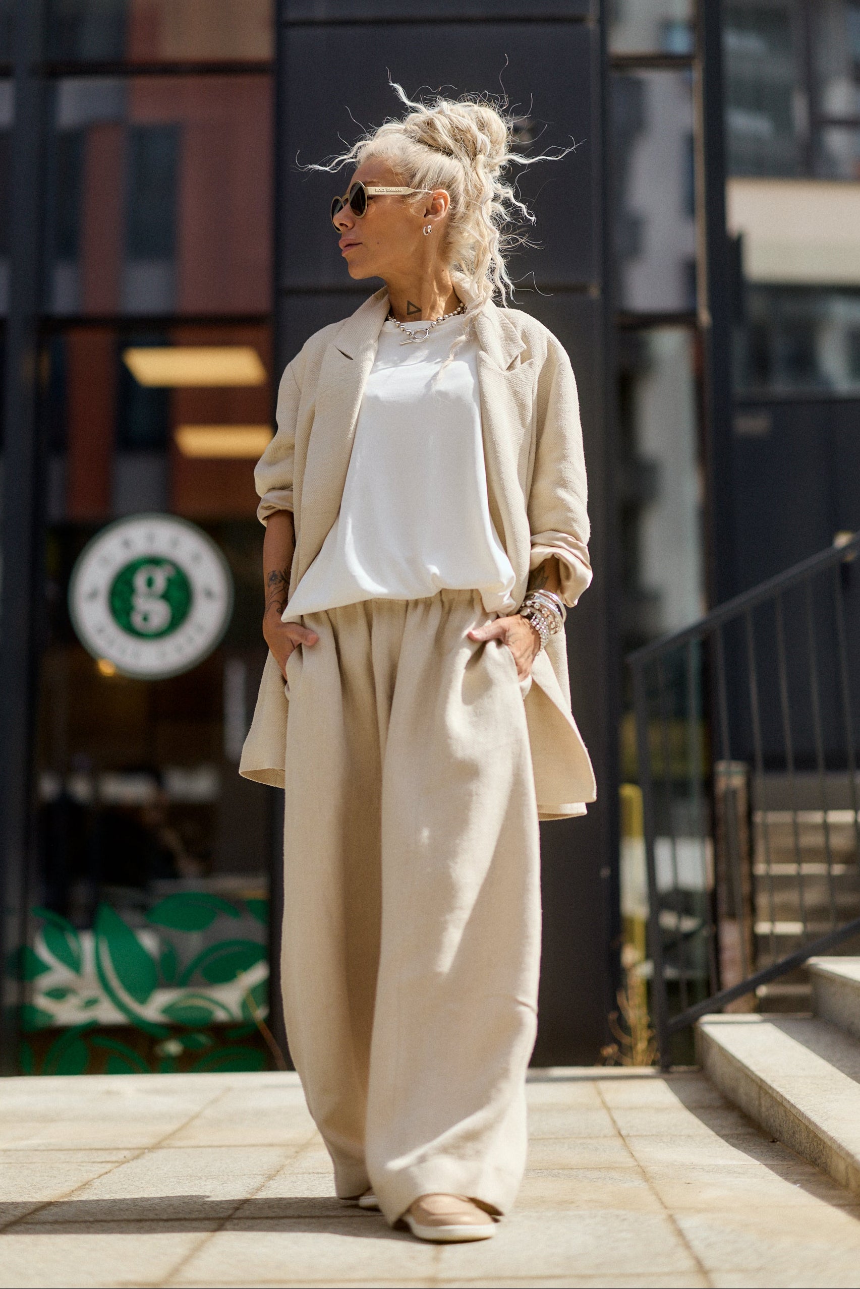 Woman in beige outfit standing on a city street