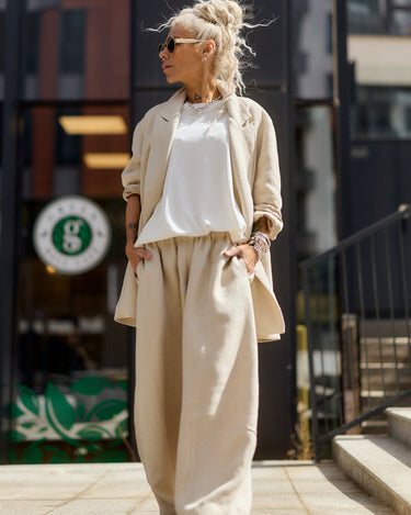 Woman in beige outfit standing on a city street