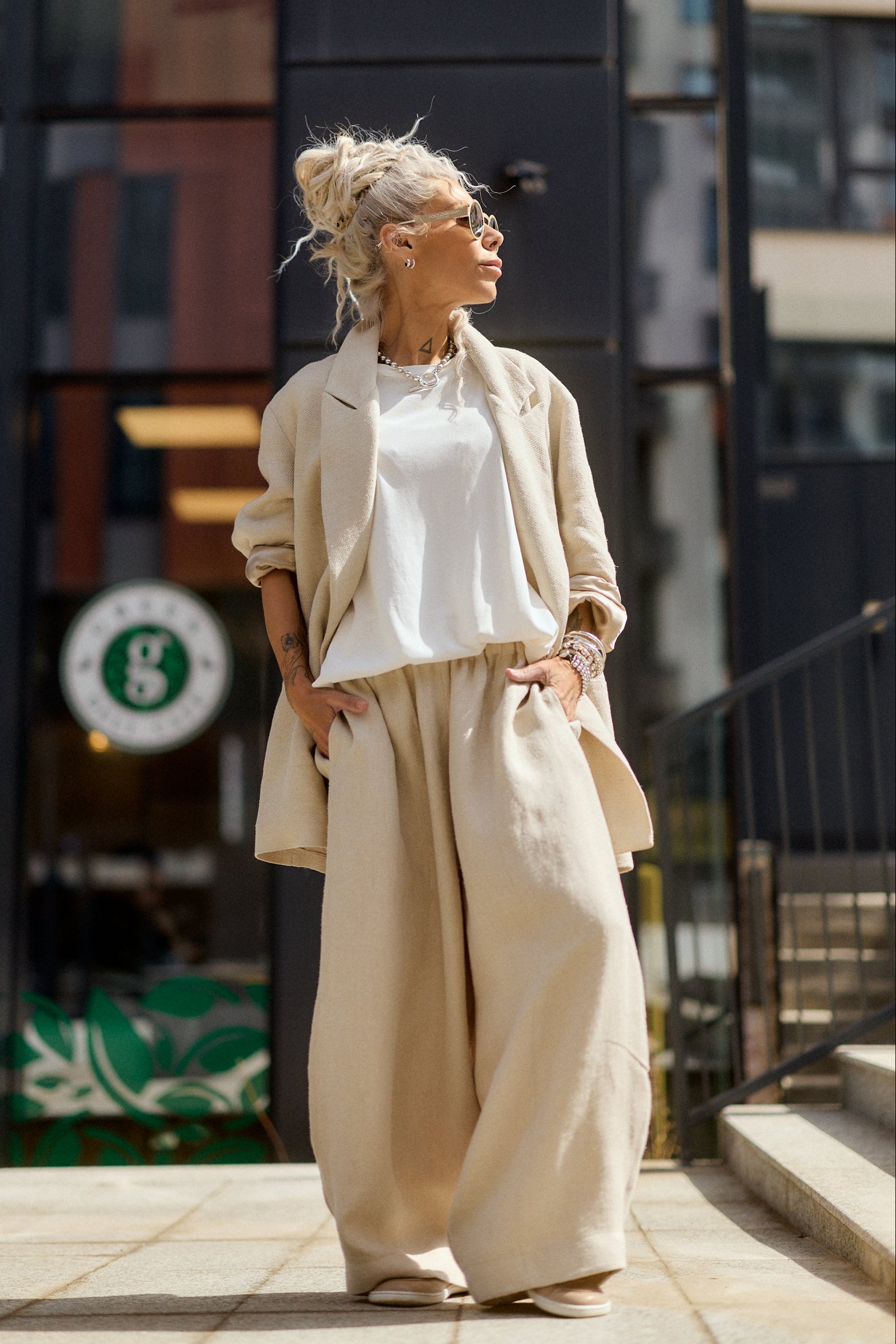 Woman in beige outfit standing on a city street