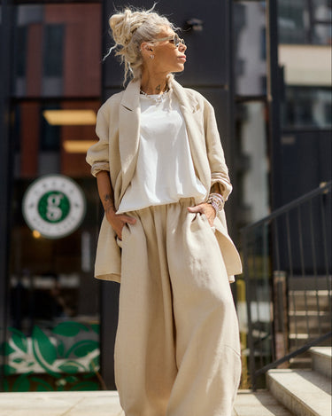 Woman in beige outfit standing on a city street
