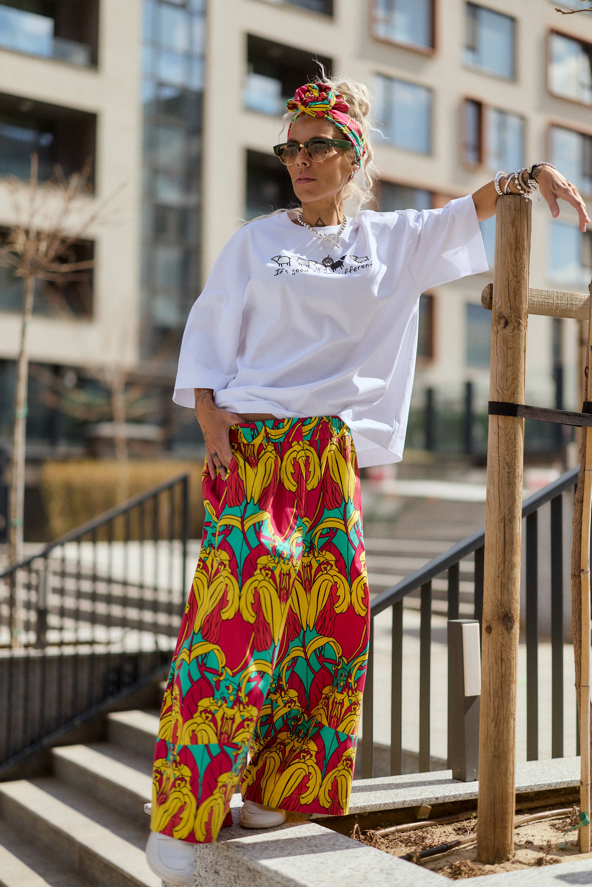 Person wearing a white t-shirt and colorful floral pants standing outdoors.