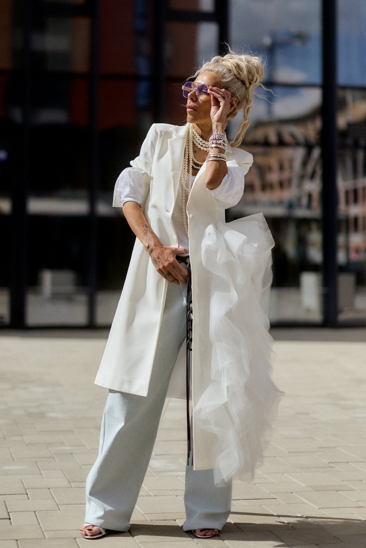 Person in a white outfit standing on a street with a blurred background