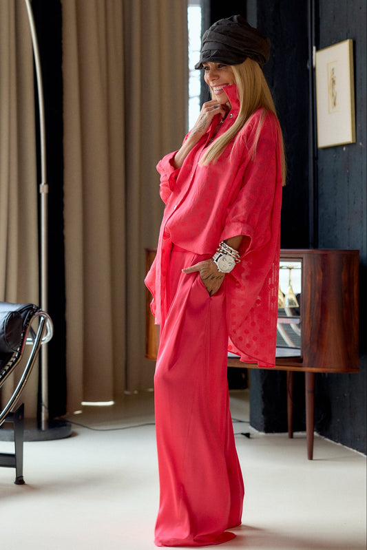 Model wearing Coral Wide-Leg Pants with a matching shirt, showcasing a chic and relaxed style in a modern interior.