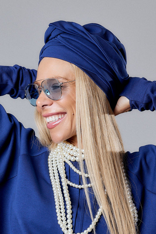 A model wearing a Blue Turban Hat with pearls and sunglasses, showcasing modern elegance and a sculptural silhouette.