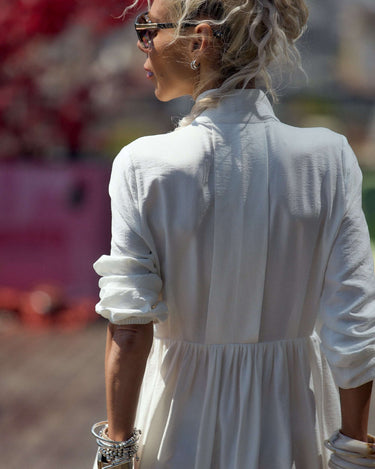 Woman wearing a Flowing White Maxi Dress with a distinctive neckline, showcasing elegant fluid movement outdoors.