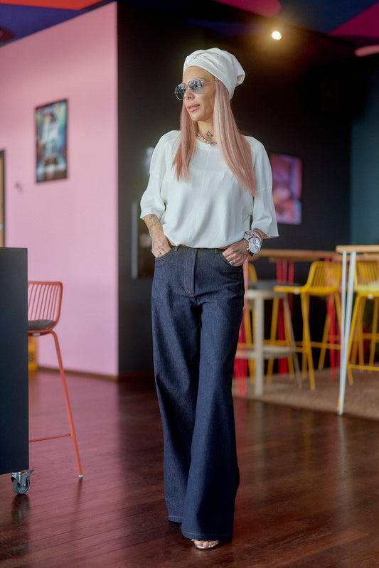 Fashionable woman wearing Wide-Leg Raw Denim Jeans with a stylish blouse and head wrap in a modern setting.