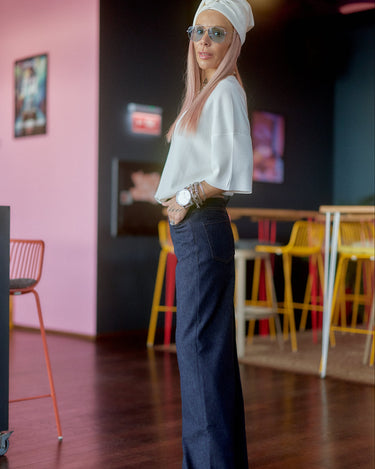 Model wearing Wide-Leg Raw Denim Jeans with a stylish top and accessories in a vibrant setting.