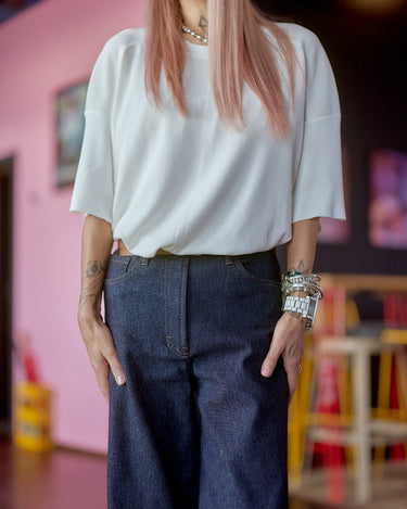 Wide-Leg Raw Denim Jeans paired with a stylish white top in a vibrant setting.