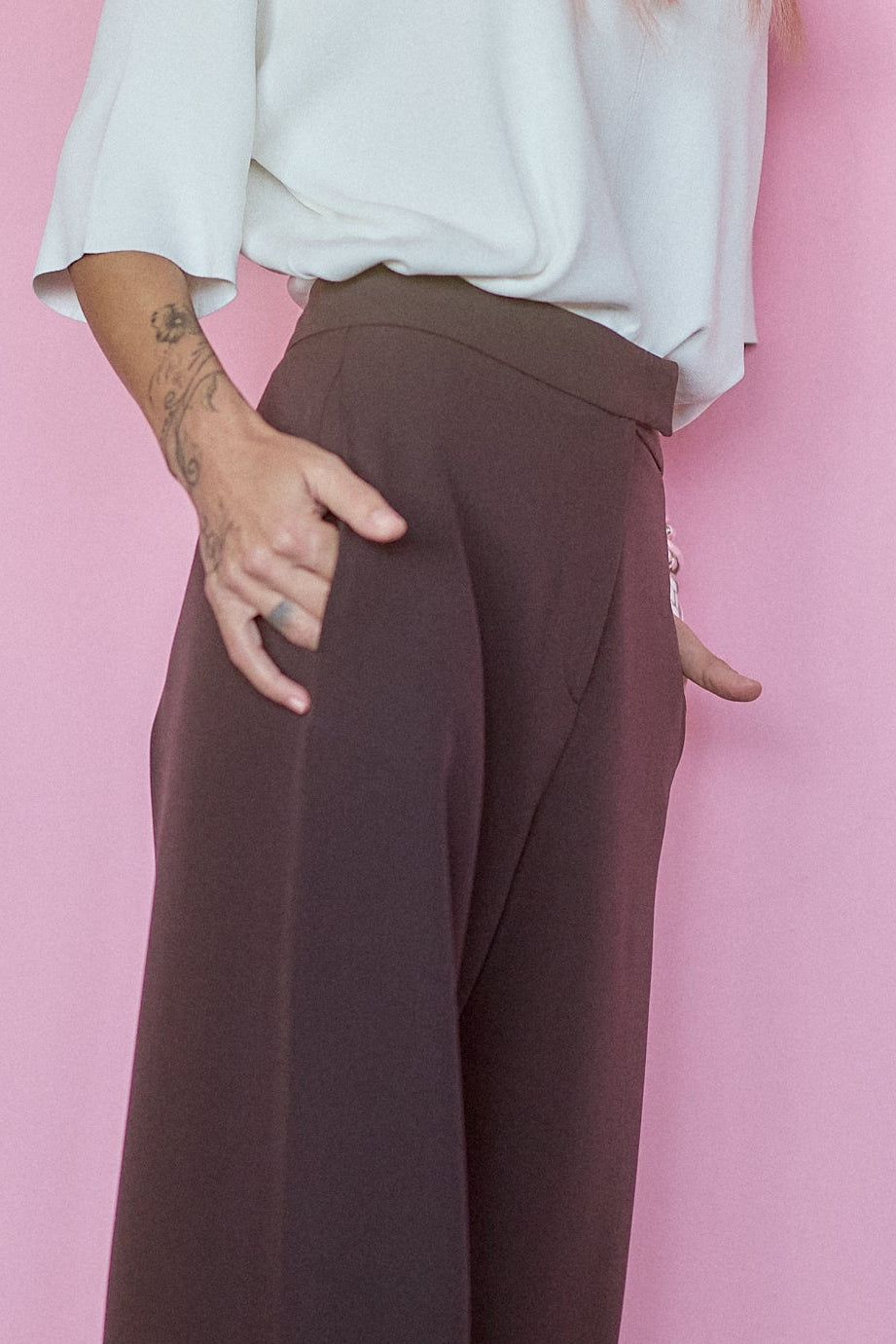 Model showcasing Wide-Leg Tailored Pants in Dark Brown against a pink background, emphasizing comfort and style.