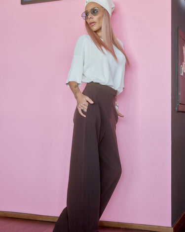 Wide-Leg Tailored Pants in Dark Brown worn by a model against a playful pink background.