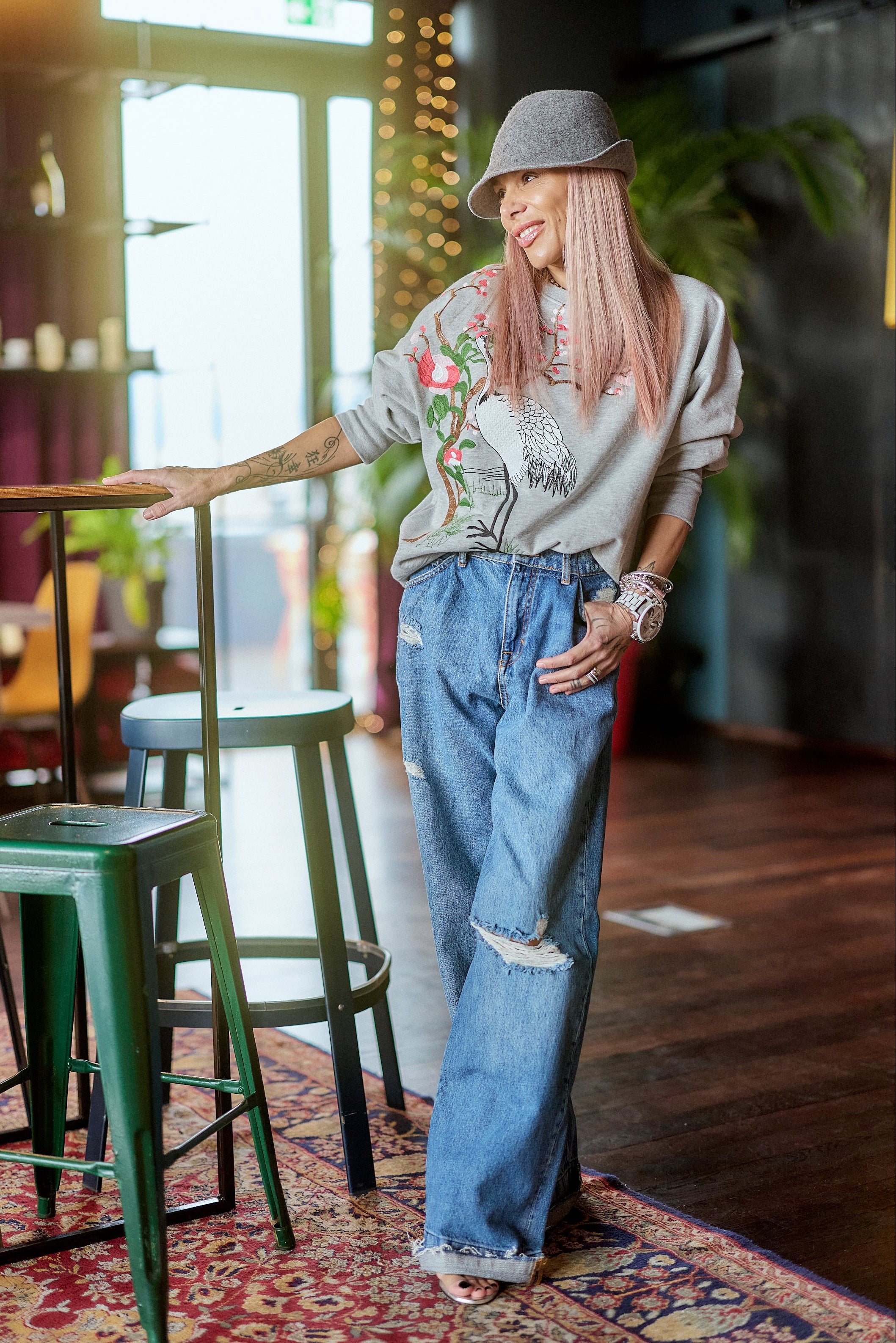 Woman wearing Distressed Wide-Leg Denim Jeans and a graphic sweatshirt in a stylish indoor setting.