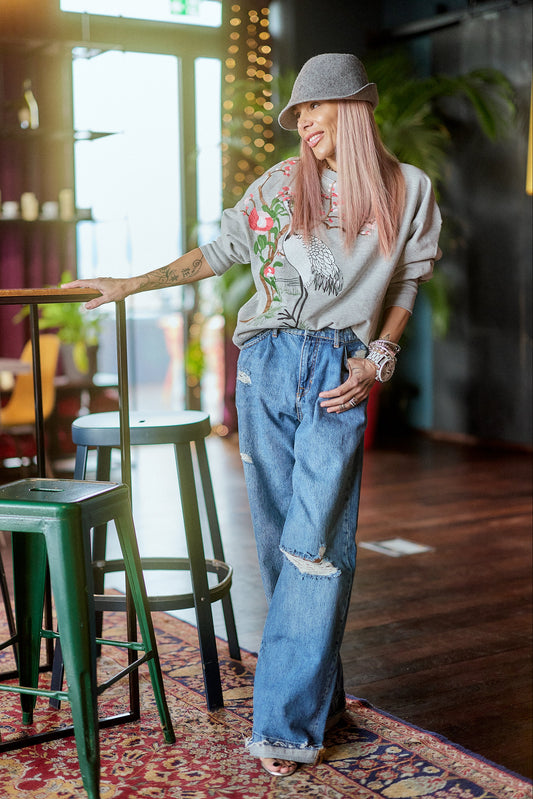 Woman wearing Distressed Wide-Leg Denim Jeans and a graphic sweatshirt in a stylish indoor setting.