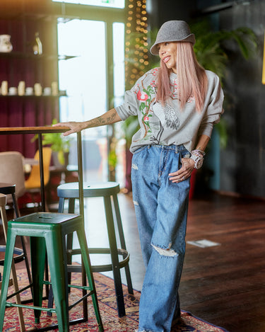 Model wearing a Printed Oversized Blouse Top and baggy jeans in a stylish cafe setting.