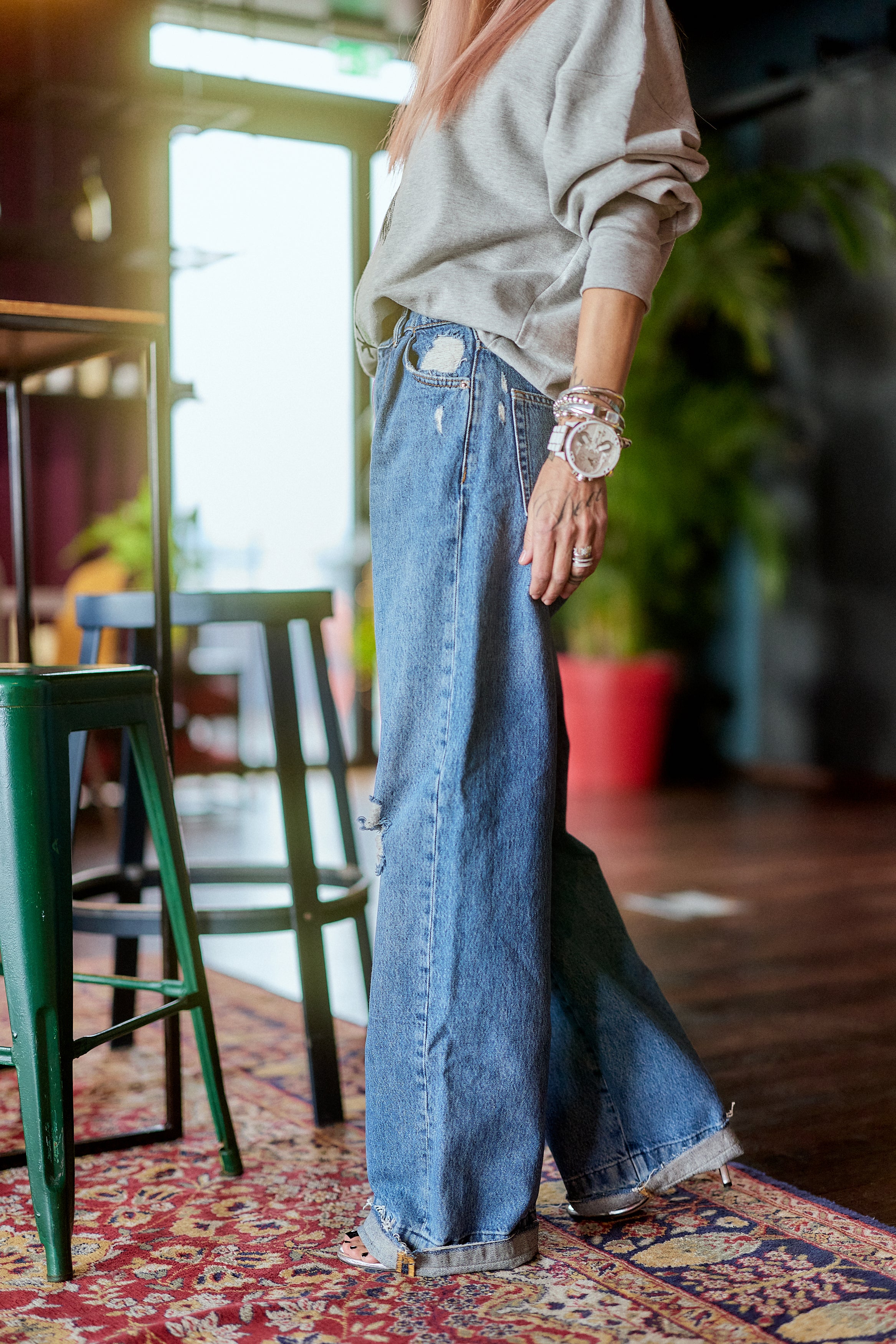 Distressed Wide-Leg Denim Jeans styled with a gray sweater in a cozy indoor setting.