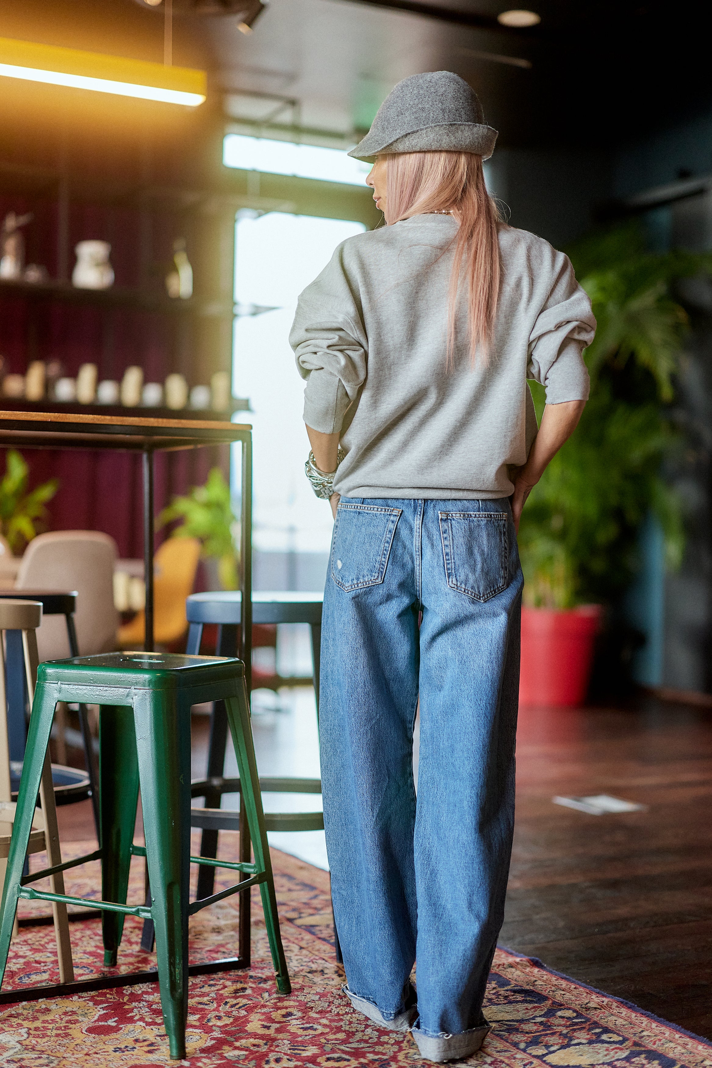 Woman wearing Distressed Wide-Leg Denim Jeans and a gray sweater in a stylish indoor setting.