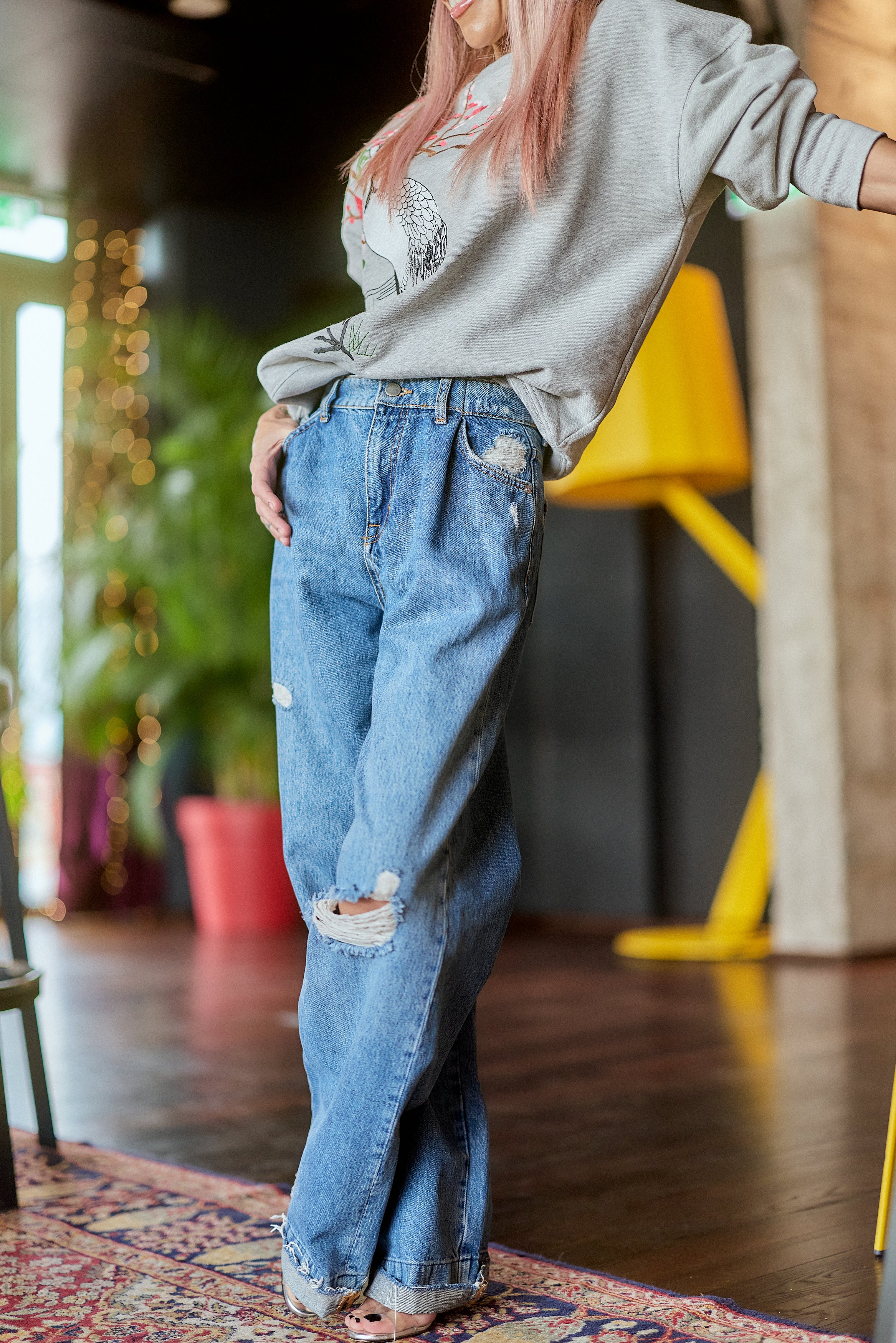 Model wearing Distressed Wide-Leg Denim Jeans with a relaxed fit, showcasing subtle distressing and a high-rise waist.