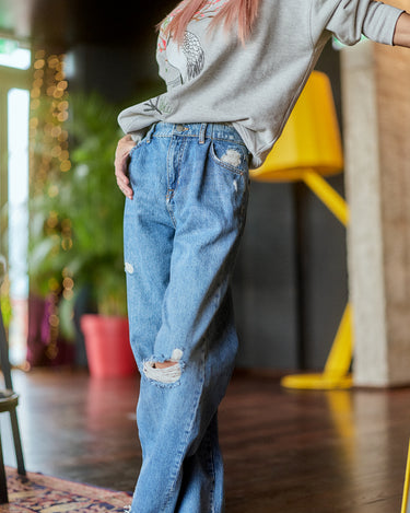 Model wearing Distressed Wide-Leg Denim Jeans with a relaxed fit, showcasing subtle distressing and a high-rise waist.