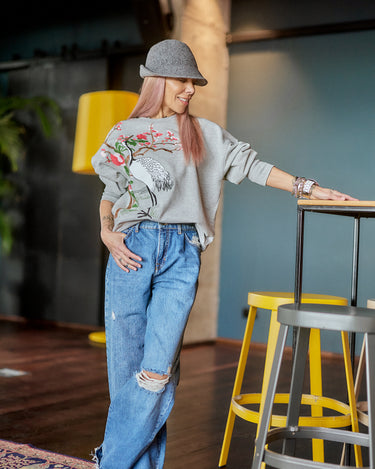 Woman wearing Distressed Wide-Leg Denim Jeans and a sweater, posing with a confident style in a modern setting.