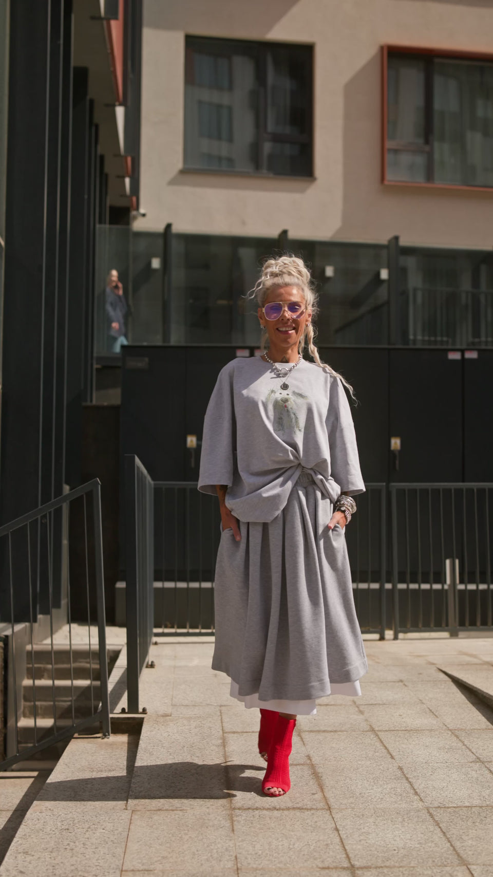 Woman wearing a Grey Pleated Midi Skirt styled with a relaxed top and bold red boots.