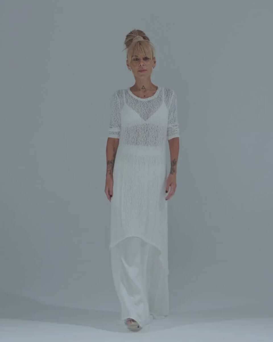 Model wearing a white maxi co-ord set with a sheer tunic over an elastic waist skirt, showcasing contemporary style.