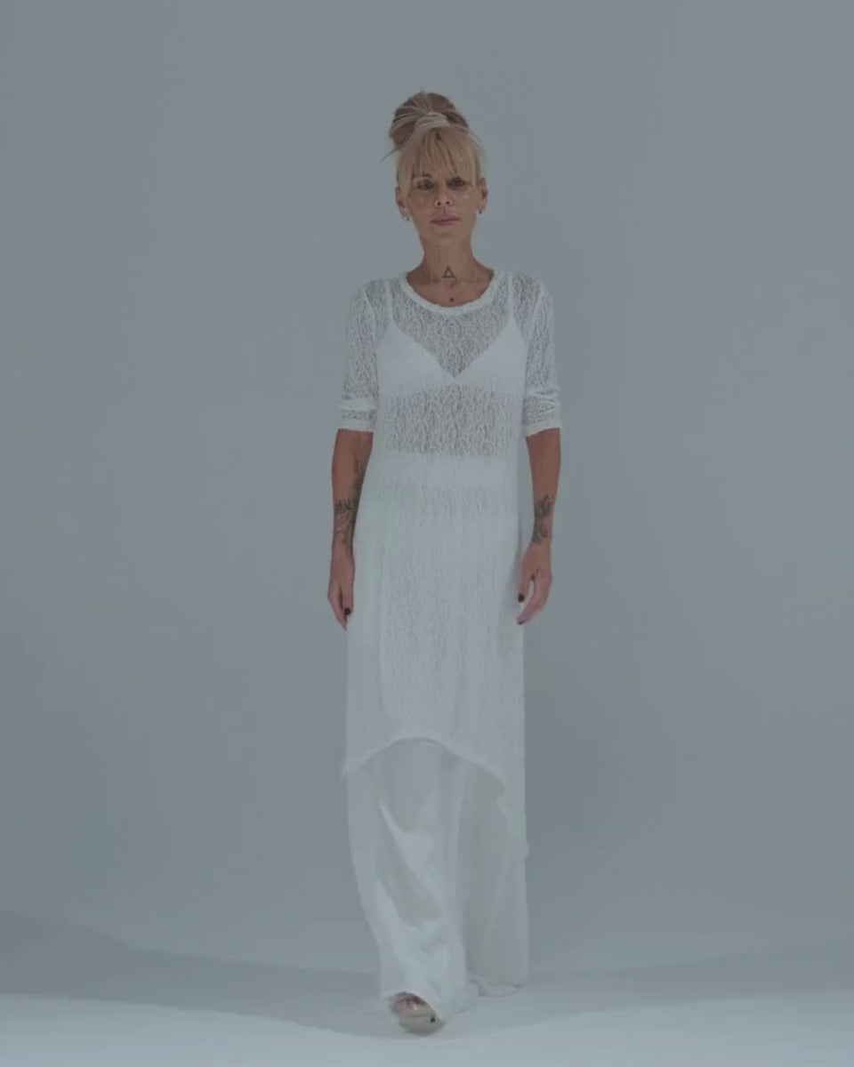 Model wearing a white maxi co-ord set with a sheer tunic over an elastic waist skirt, showcasing contemporary style.