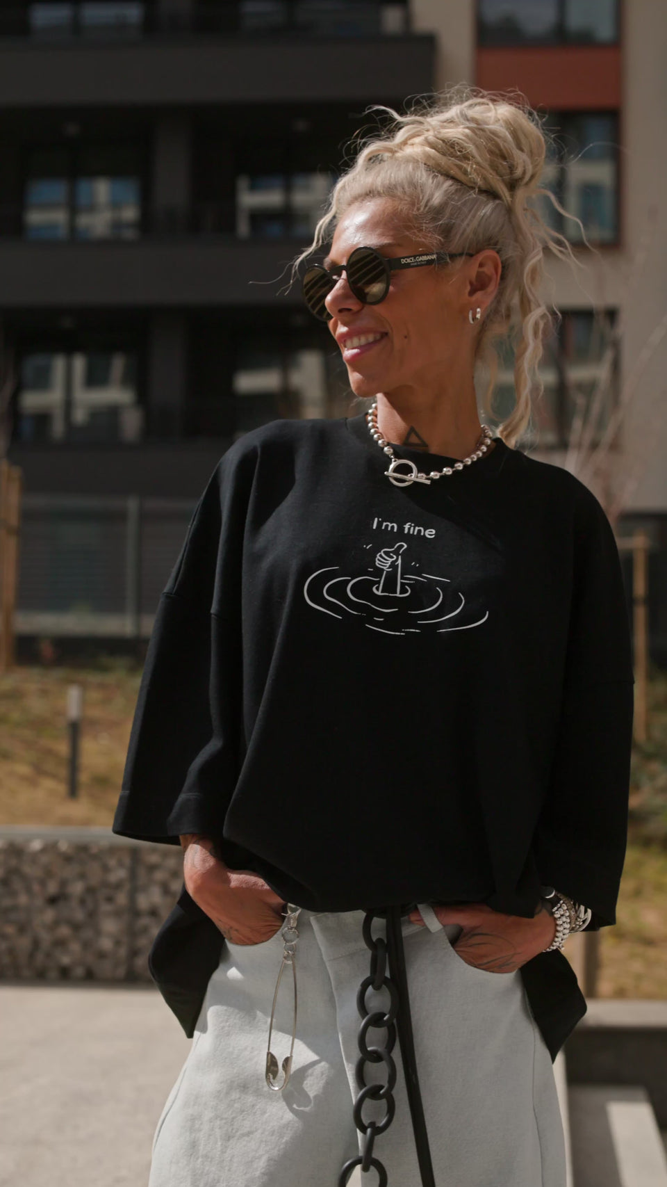 Black Oversized “I’m Fine” Graphic T-Shirt worn by a smiling woman, showcasing a sinking gesture design.